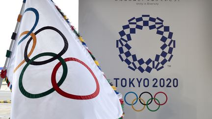 Le drapeau oympique devant le logo des Jeux Olympiques de Tokyo 2020 (KAZUHIRO NOGI / AFP)