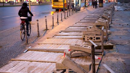 Un cycliste passe &agrave; c&ocirc;t&eacute; d'une cl&ocirc;ture renvers&eacute;e par la violence du vent, le 6 d&eacute;cembre 2013, &agrave; Berlin (Allemagne). (KAY NIETFELD / AFP)