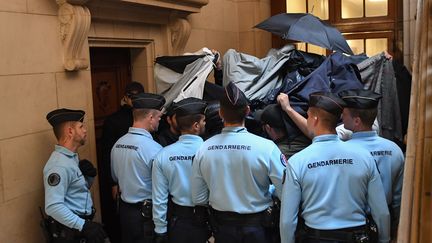 Des gendarmes encadrent les prévenus qui se protègent des caméras et des appareils photo par des parapluies et des blousons, le 20 septembre 2017, à Paris. (ERIC FEFERBERG / AFP)