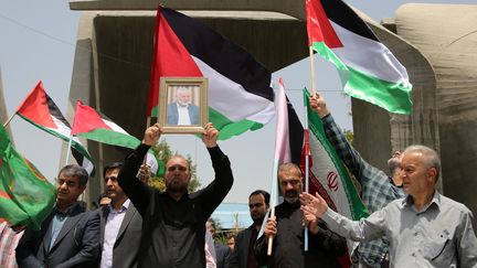 Des chercheurs de l'université de Téhéran brandissent le portrait du leader du Hamas Ismaïl Haniyeh, au milieu de drapeaux palestiniens et iraniens, après sa mort en Iran, le 31 juillet 2024. (FATEMEH BAHRAMI / ANADOLU / AFP)