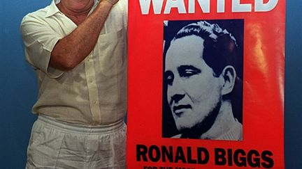 Ronnie Biggs montrant l'affiche de son livre alors qu'il était encore au Brésil en 1994 (© AFP)