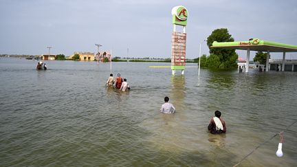 Des&nbsp;sinistrés traversent l'eau pour rentrer chez eux après les fortes pluies de mousson dans le district de Dadu, dans la province du Sindh, le 7 septembre 2022. (AAMIR QURESHI / AFP)