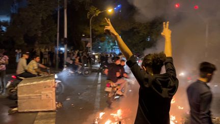 Un manifestant lève les bras et fait le signe de la victoire lors d'une manifestation à&nbsp;Téhéran, le 19 septembre 2022,&nbsp;pour Mahsa Amini, une jeune femme décédée après avoir été arrêtée par la police des moeurs de la République islamique le 16 septembre 2022.&nbsp; (AFP)