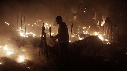 Des occupants du camp de migrants de Moria, sur l'île grecque de Lesbos, tentent d'éteindre un incendie, le 25 novembre 2016. (AFP)