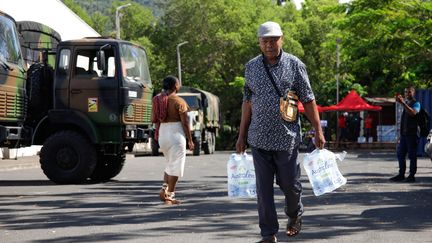 Un homme transporte des packs d'eau, le 21 septembre 2023 à Mayotte. (CHAFION MADI / AFP)