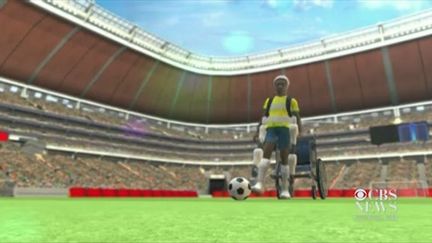 Capture d'&eacute;cran de la vid&eacute;o de CBS News simulant le coup d'envoi de la Coupe du monde 2014 donn&eacute; par un parapl&eacute;gique &eacute;quip&eacute; d'un exosquelette. (CBS NEWS )