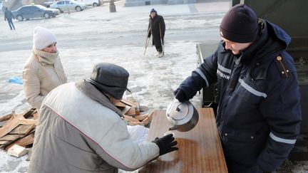 Un employ&eacute; des services sociaux sert un th&eacute; chaud &agrave; un homme dans un abri r&eacute;cemment ouvert &agrave; Lviv (Ukraine), le 30 janvier 2012. (YURIY DYACHYSHYN / AFP)