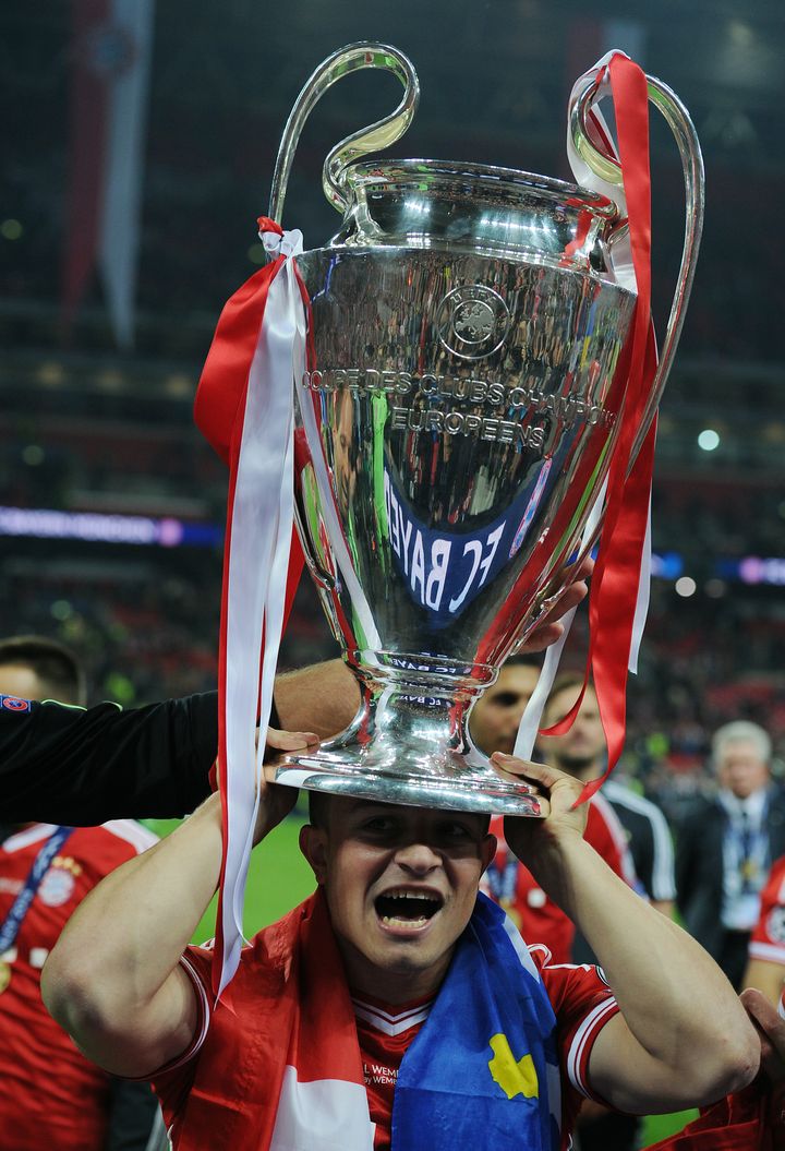 Le joueur du Bayern Munich Xherdan Shaqiri se coiffe de la Ligue des champions en portant autour du cou les drapeaux albanais et kosovar, lors de la finale gagnée contre Dortmund, le 25 mai 2013, à Londres. (CHRIS BRUNSKILL LTD / CORBIS SPORT / GETTY IMAGES)