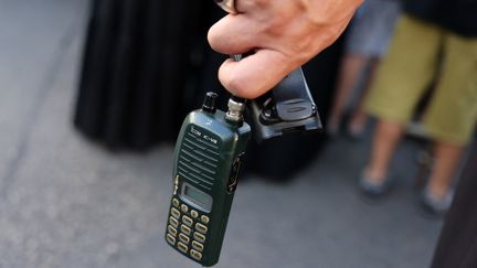 Un homme tient un talkie-walkie après avoir retiré la batterie pendant les funérailles des personnes tuées lorsque des centaines de bipeurs ont explosé lors d'une vague meurtrière au Liban, le 18 septembre 2024. (ANWAR AMRO / AFP)