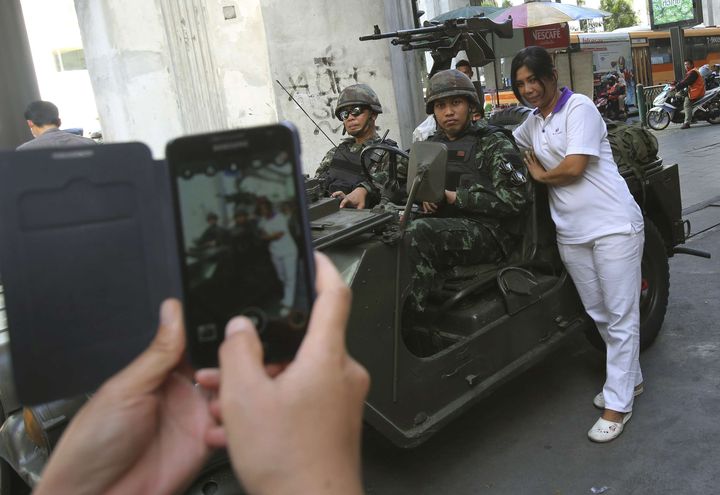 Une Tha&iuml;landaise pose avec des militaires, &agrave; Bangkok (Tha&iuml;lande), le 20 mai 2014. (SAKCHAI LALIT / AP / SIPA)