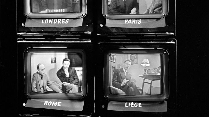 Sur quatre écrans de contrôle, apparaissent en multiplex les quatre visages des étudiants européens réunis par la technique, lors de l'émission télévisée "Cinq colonnes à la une", lancée en 1959. (DANIEL FALLOT / INA / AFP)