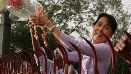 Alors leader de l'opposition birmane, Aung San Suu Kyi reçoit un bouquet de fleurs de la part de ses partisans, le 13 novembre 2010. La police a ce jour-là enlèvé les barrières posées devant la maison&nbsp;de la prix Nobel de la paix, permettant sa libération après 15 ans de résidence surveillée. (SOE THAN WIN / AFP)