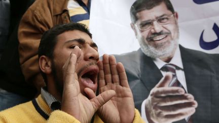 Un supporter du pr&eacute;sident &eacute;gyptien Mohamed Morsi (sur l'affiche), manifeste, le 5 d&eacute;cembre, au Caire.&nbsp; (HASSAN AMAR / SIPA)