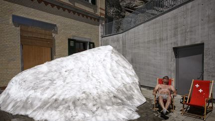 Un homme profite d'un bain de soleil au c&ocirc;t&eacute; d'un amas de neige sur &nbsp;le mont Pilatus (Suisse), le 18 juin 2013. (MAXPPP)