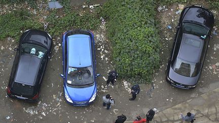 Des policiers et badauds se tiennent devant un v&eacute;hicule abandonn&eacute; enti&egrave;rement recouvert de v&eacute;g&eacute;tation &agrave; Chengdu (Chine), le 17 octobre 2013. (REUTERS)