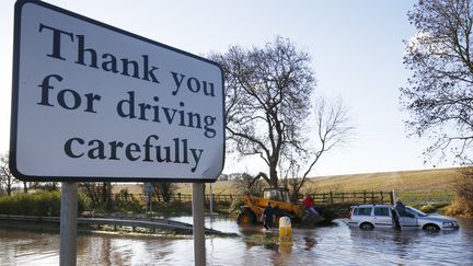 Un engin tente de tracter une voiture prise dans les inondations, dans le centre de l'Angleterre, le 25 novembre. (DARREN STAPLES / REUTERS)