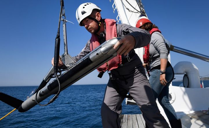 Un membre d'équipage de l'André Malraux jette un sonar à l'eau au large de Brest lors des premières recherches en 2018. (FRED TANNEAU / AFP)