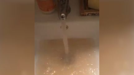 De l'eau trouble sortant d'un robinet, sur une capture d'écran d'une vidéo publiée sur Twitter, le 29 septembre 2019, par une jeune femme vivant à Rouen. (JUNOEDACAT / TWITTER)