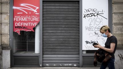 Une personne passe devant un magasin qui a fermé définitivement, le 8 juin 2020 à Paris. (ALAIN JOCARD / AFP)