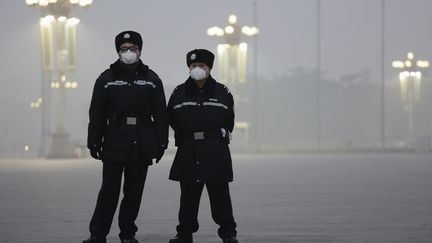 Des policiers portent un masque pour se protéger de la pollution sur la place Tiananmen, le 1er décembre à Pékin (Chine). (DAMIR SAGOLJ / REUTERS)