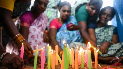 Des femmes allument des bougies lors des commémorations de la catastrophe sur cette même plage de Pattinapakkam (Inde). (R.SATISH BABU / AFP)