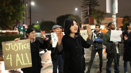 "Justice 4 all" : justice pour tous ! proclame, &agrave; l'autre bout des Etats-Unis, cette manifestante &agrave; Los Angeles. La rel&acirc;che du policier blanc a d'autant plus mis en col&egrave;re les manifestants qu'elle fait suite &agrave; une d&eacute;cision de justice similaire &agrave; Ferguson, dans le Missouri. L'officier Darren Wilson n'a pas &eacute;t&eacute; poursuivi apr&egrave;s avoir tu&eacute; un adolescent noir, Michael Brown. (DAVID MCNEW / GETTY IMAGES NORTH AMERICA/AFP)