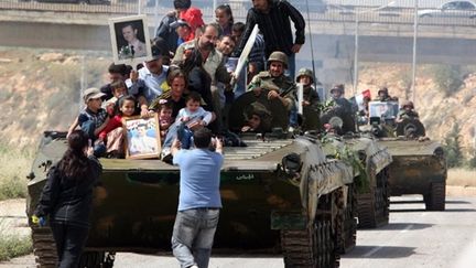 Des Syriens brandissent des portraits du président Bashar al-Assad devant un char sur la route de Deraa, le 5 mai 2011. (AFP/LOUAI BESHARA)