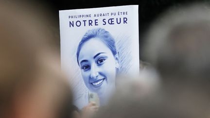 Un personne brandit, le 29 septembre 2024, une pancarte avec le portrait de Philippine, 19 ans, retrouvée morte dans le bois de Boulogne, dans l'ouest de Paris. (GEOFFROY VAN DER HASSELT / AFP)