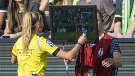 Une arbitre aidée par la vidéo pour juger d'une action, dans le championnat d'Allemagne, le 18 mai 2023. (DAVID INDERLIED / AFP)