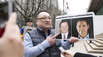 Le responsable d'une association pro-démocratie montre les portraits des Canadiens Michael Spavor et Michael Kovrig, lors d'un rassemblement de soutien à Vancouver en mars 2019. (JASON REDMOND / AFP)