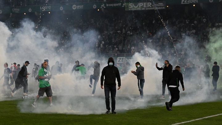 Des supporters stéphanois sur la pelouse du stade Geoffroy-Guichard, à l'issue de la défaite face à Auxerre, synonyme de relégation en Ligue 2, le 29 mai 2022. (JEAN-PHILIPPE KSIAZEK / AFP)