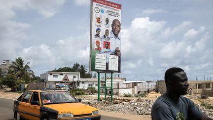 Un homme passe à vélo devant une affiche électorale à Dakar, le 27 juillet 2022, alors que le Sénégal vote le 31 juillet 2022 pour l'élection des 165 membres de l'Assemblée nationale. (JOHN WESSELS / AFP)