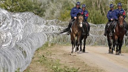 Des policiers hongrois patrouillent, le 16 septembre 2015, près du village d'Asotthalom, le long de la barrière de fils de fer barbelés mise en place à la frontière avec la Serbie. (REUTERS - Stoyan Nenov)