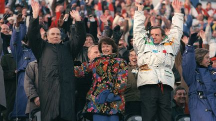 Le pr&eacute;sident de la R&eacute;publique fran&ccedil;aise Fran&ccedil;ois Mitterrand (G), son &eacute;pouse Danielle et l'ancien champion olympique de ski alpin Jean-Claude Killy (D) font la hola lors de la c&eacute;r&eacute;monie d'ouverture des Jeux olympiques d'hiver d'Albertville, le 8 f&eacute;vrier 1992. (AFP)