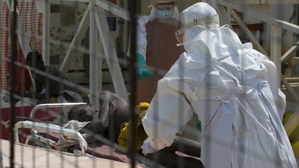 Un m&eacute;decin pousse un brancard sur lequel est allong&eacute; un patient de 16 ans atteint d'Ebola, le 22 d&eacute;cembre 2014, en&nbsp;Sierra Leone.&nbsp; (BAZ RATNER / REUTERS)