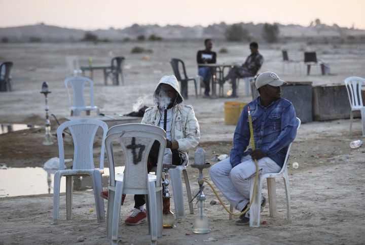 Des migrants africains du centre de rétention de Holot dans le sud d'Israël, fumant le narguilé dans un café à ciel ouvert, improvisé aux abords du camp, le 3 septembre 2017. (MENAHEM KAHANA/AFP)