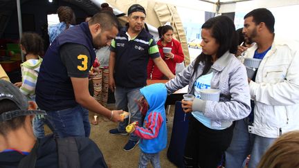 Les migrants venezueliens reçoivent de la nourriture pendant qu'ils attendent à Huaquillas en Équateur de pouvoir passer au Pérou. (JOSE JACOME / EFE)