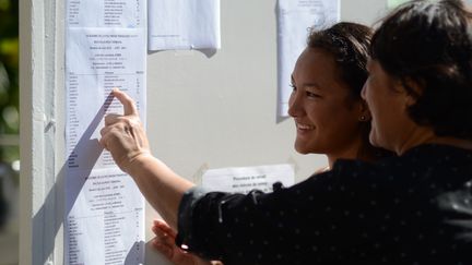 Ranitea Gobrait, la bachelière major de Polynésie, regarde avec sa mère, les résultats du bac à Papeete, le 6 juillet 2018. La jeune fille a obtenu la note de 20,32/20. (MIKE LEYRAL / AFP)