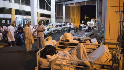 Patients et employés attendent à l'extérieur du CHU de Guadeloupe après son évacuation suite à un incendie, le 28 novembre 2017. (HELENE VALENZUELA / AFP)