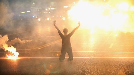 Des gaz lacrymog&egrave;nes pleuvent sur une manifestante &agrave; genoux, le 17 ao&ucirc;t 2014. (SCOTT OLSON / GETTY IMAGES / AFP)