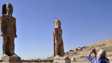 Une touriste prend une photo des 2 statues du pharaon Amenhotemp III, au temple de Louxor, le 14/12/2014
 (RADWAN ABU-ELMAGD / AFP)