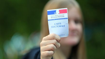 Une adolescente montre une carte d'électeur.&nbsp;Le droit de vote à 16 ans ? (Illustration) (VANESSA MEYER / MAXPPP)