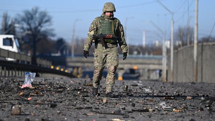 Un soldat ukrainien marche dans les débris qui couvrent le sol à l'ouest de Kiev le 26 février 2022. (DANIEL LEAL / AFP)