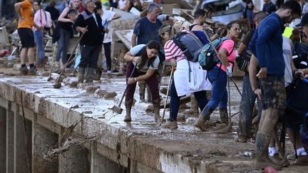 Des volontaires évacuent de la boue dans le lit de la Rambla del Poyo, un cours d'eau qui traverse la commune de Paiporta, au sud de Valence. (JOSE JORDAN / AFP)