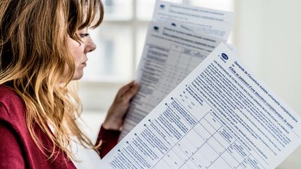 Une femme consulte un formulaire de demande de prise en charge par la Couverture maladie universelle (CMU) le 8 mars 2018. (GARO / PHANIE / AFP)