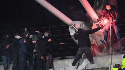 Des supporters escaladent des grilles avec un fumigène lors du match entre le PFC et l'OL, vendredi 17 décembre, au stade Charléty. (BERTRAND GUAY / AFP)