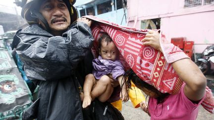 Un sauveteur &eacute;vacue un b&eacute;b&eacute; pendant le passage du typhon Rammasun &agrave; Manille (Philippines), le 16 juillet 2014. (MAXPPP)