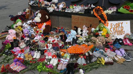 Des chaussures et des jouets pour enfants sont placés au pied de la flamme du centenaire pour rendre au hommage aux enfants autochtones dont les restes de 215 corps ont été retrouvés dans un pensionnat de Colombie-Britannique (1er juin 2021). (DAVE CHAN / AFP)