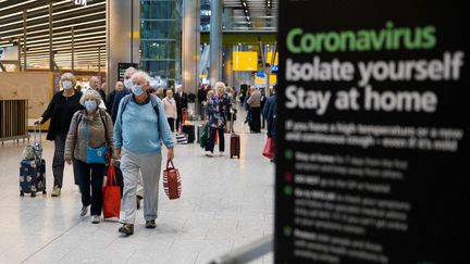 Des passagers à l'aéroport d'Heathrow à Londres, le 19 mars 2020. (TOLGA AKMEN / AFP)