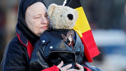 Une fan assiste à l'hommage avec une peluche blottie contre son corps, sur les Champs-Elysées. (GONZALO FUENTES / REUTERS)